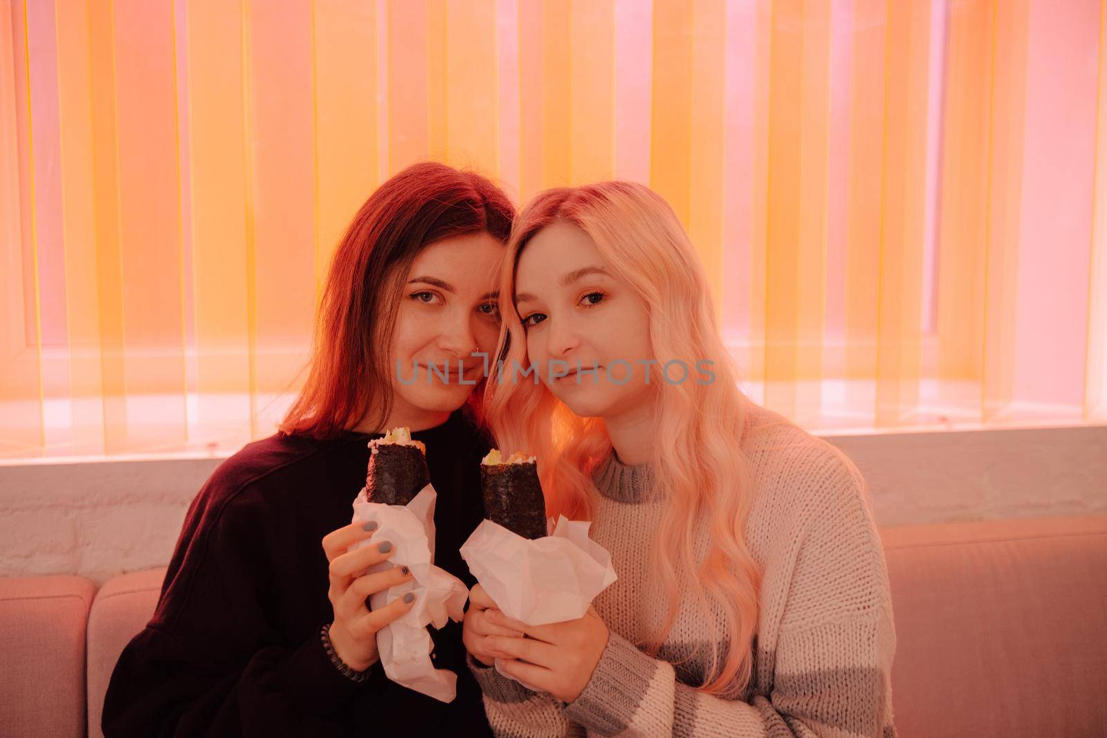 LGBT Lesbian couple eat sushi rolls in asian cafe with red light