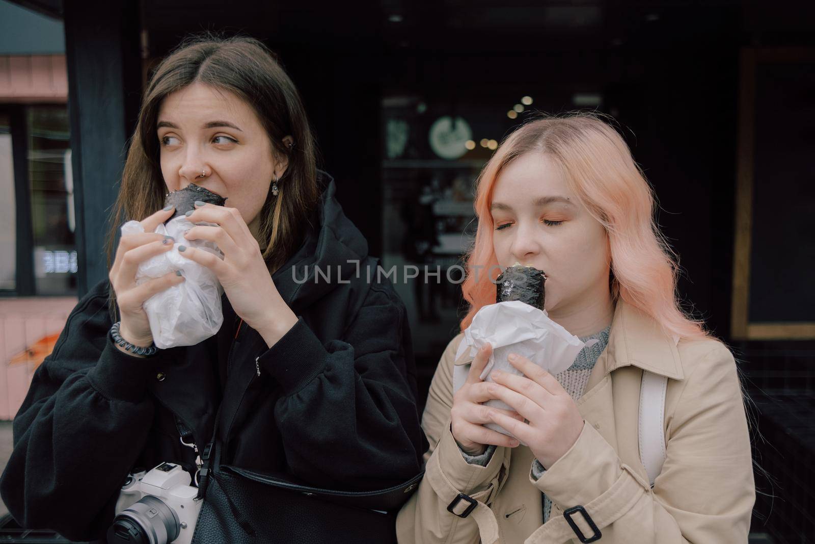 LGBT Lesbian couple eat sushi rolls on the walk asian cafe. street food concept