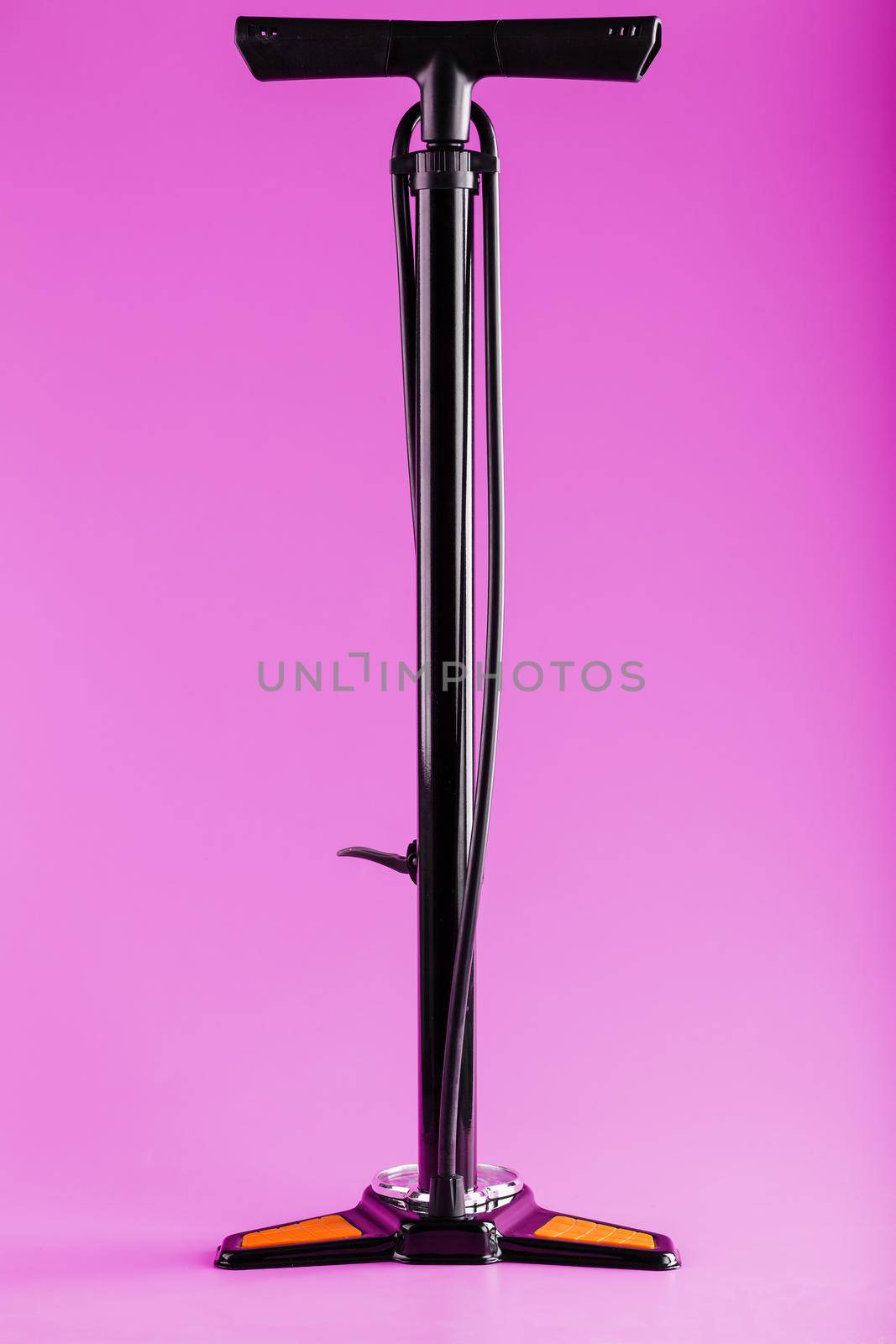 Black bicycle manual air pump for pumping wheels on a pink background with a vertical composition