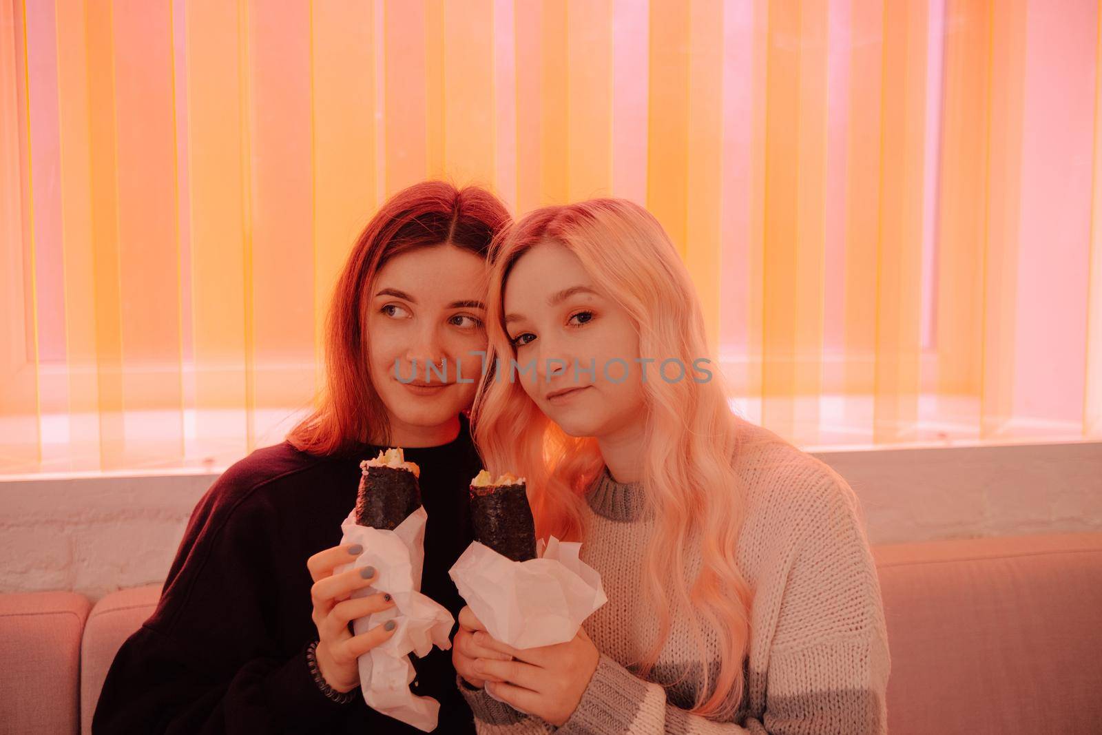 LGBT Lesbian couple eat sushi rolls in asian cafe by Symonenko