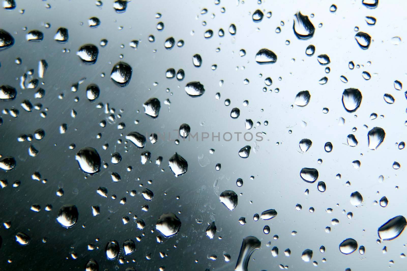 Raindrops on window pane on a cold and cloudy day of winter