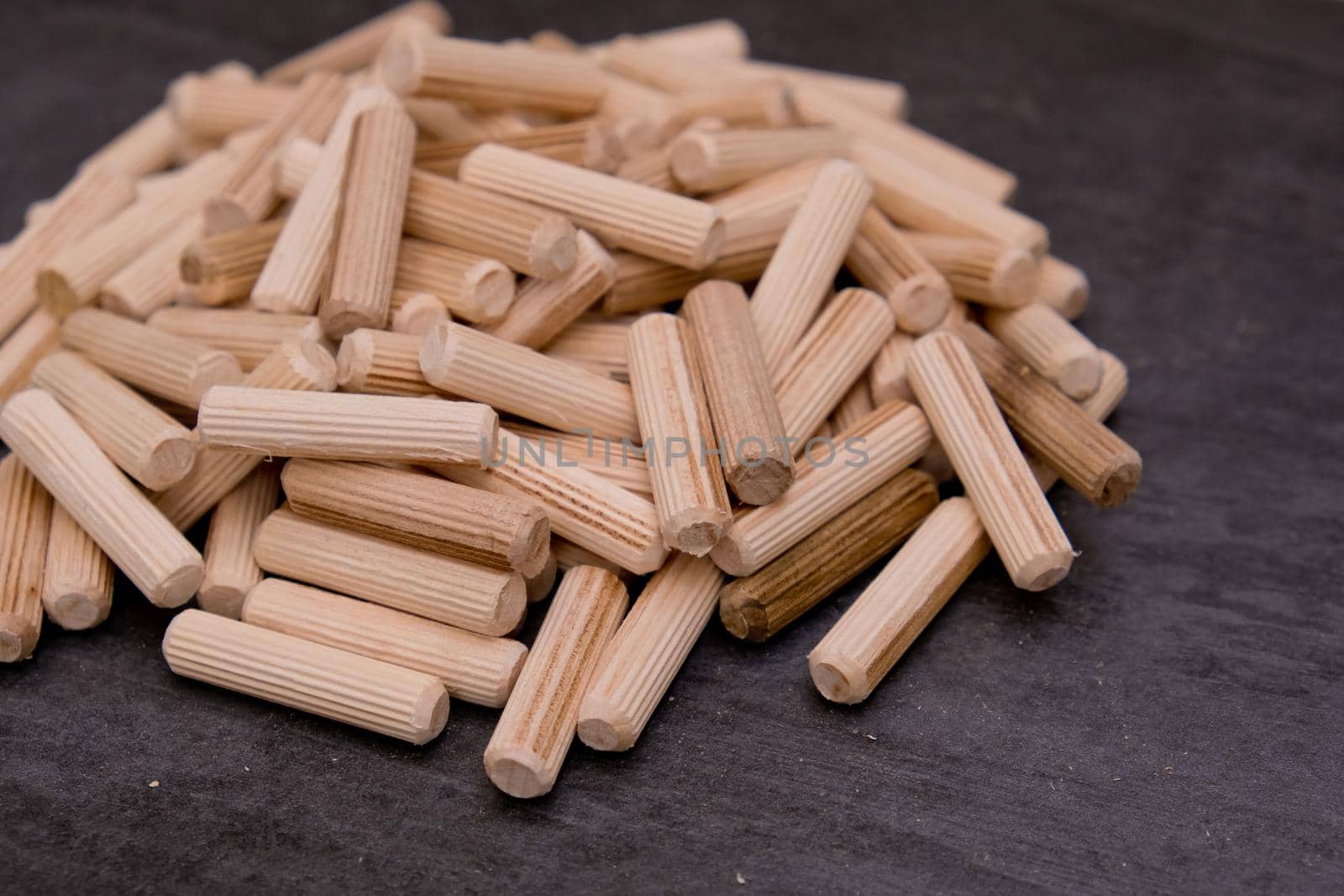 View of a grouping of wooden dowels on grey background. Close-up. Selective focus.