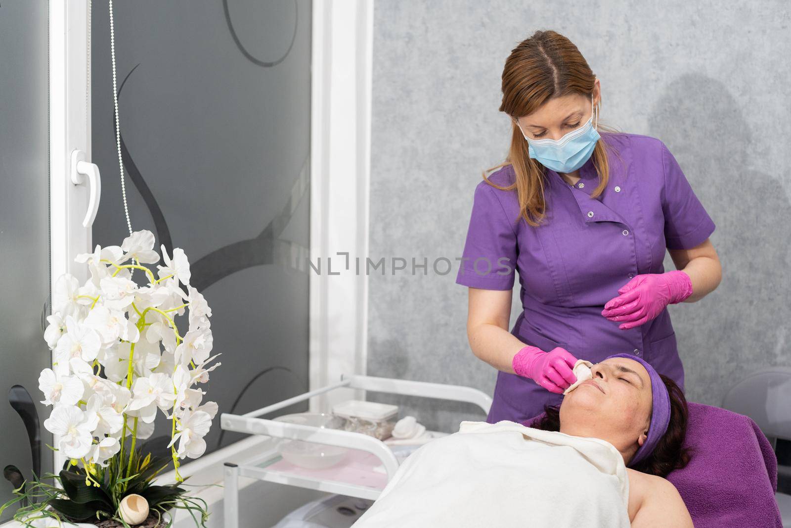 After washing the face with the gel, the beautician wipes dry the remains of the wet gel from the client's face.
