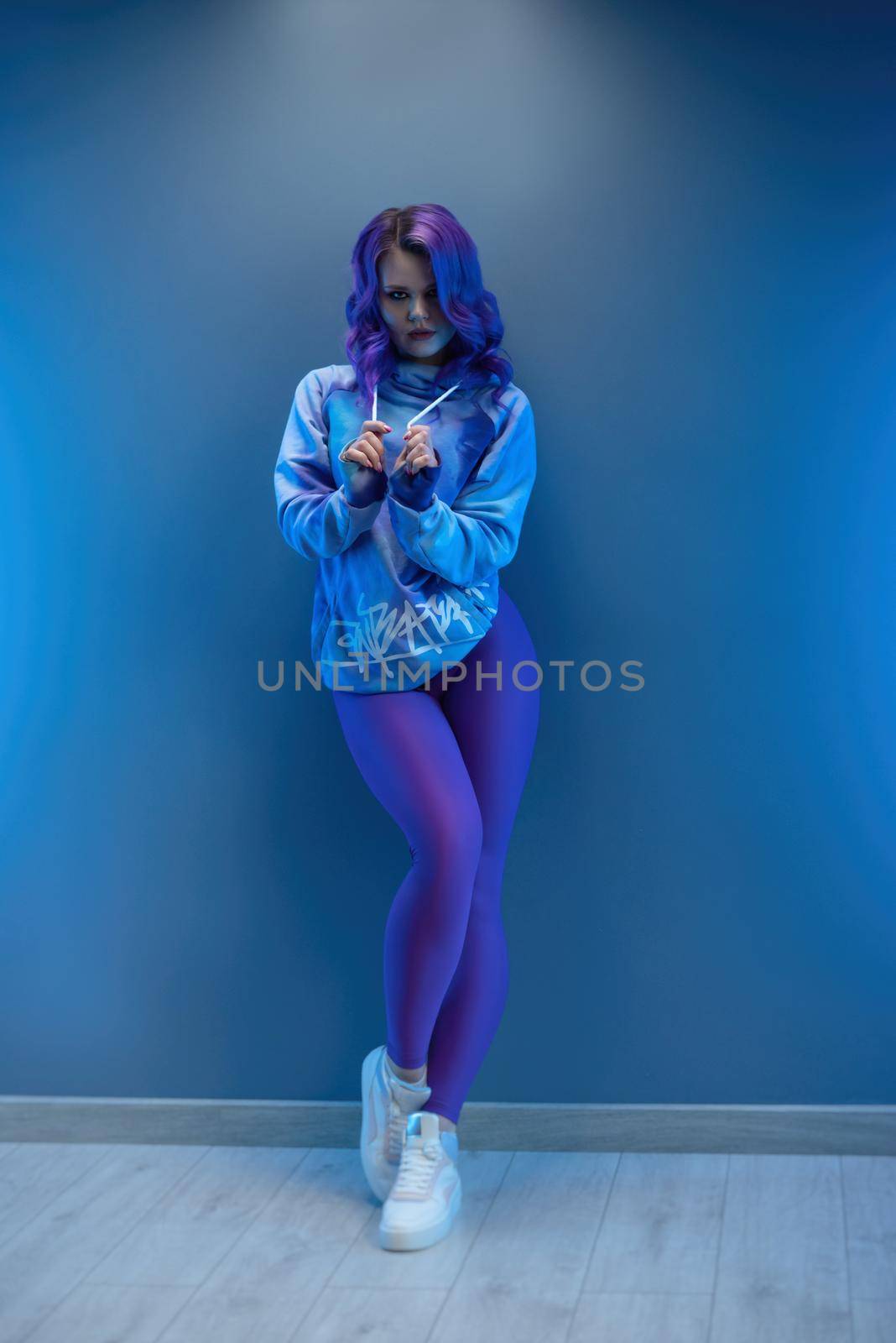 girl in stylish purple sportswear and with purple hair poses sexually