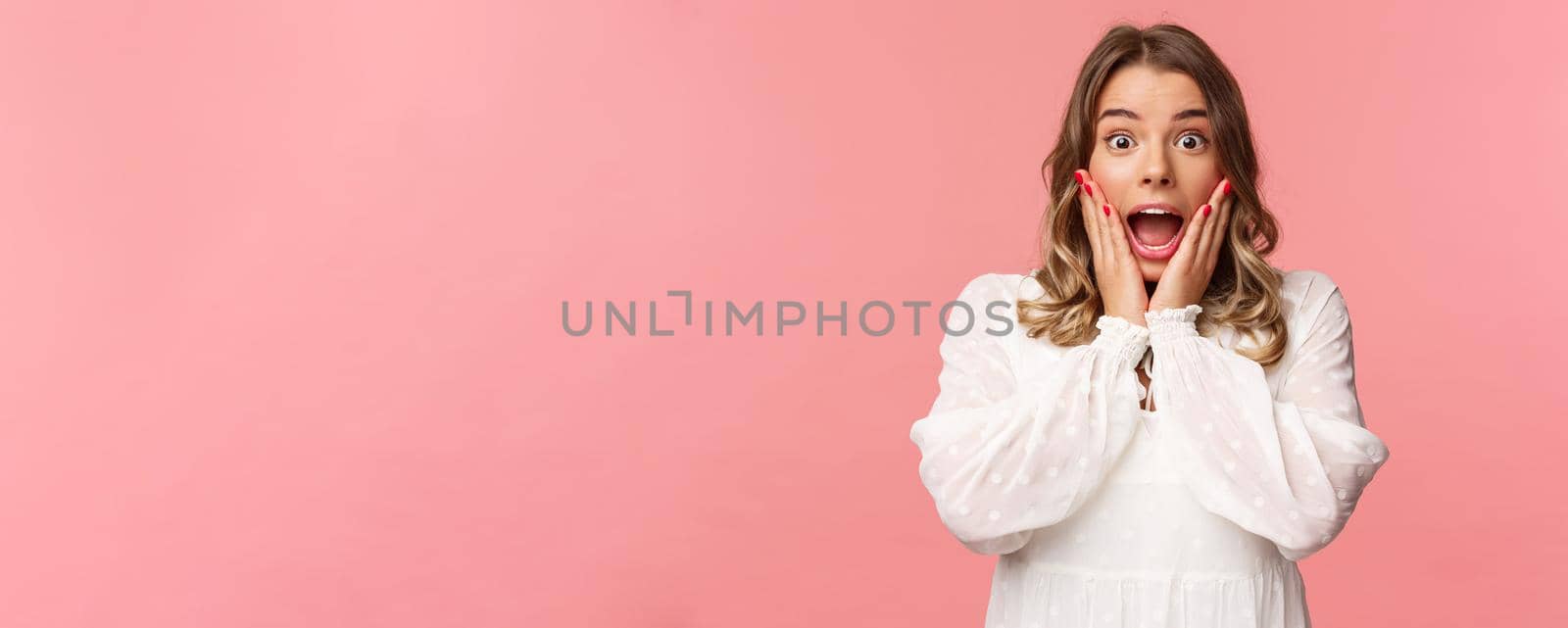 Happy and surprised blond girl hear awesome news, gasping speechless staring camera with hands on cheeks, being impressed and stunned over great event, standing pink background by Benzoix