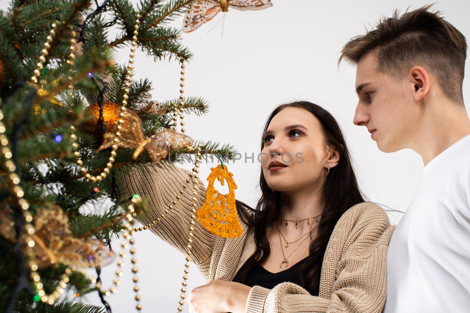 Couple in love while decorating the Christmas tree for Christmas. Smiling young people.