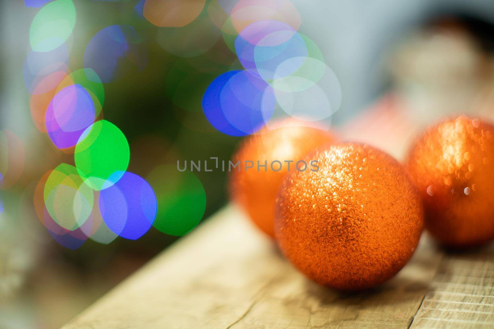 Decoration on the fireplace for Christmas. Shimmering Christmas balls in gold. Christmas tree lights in the background.