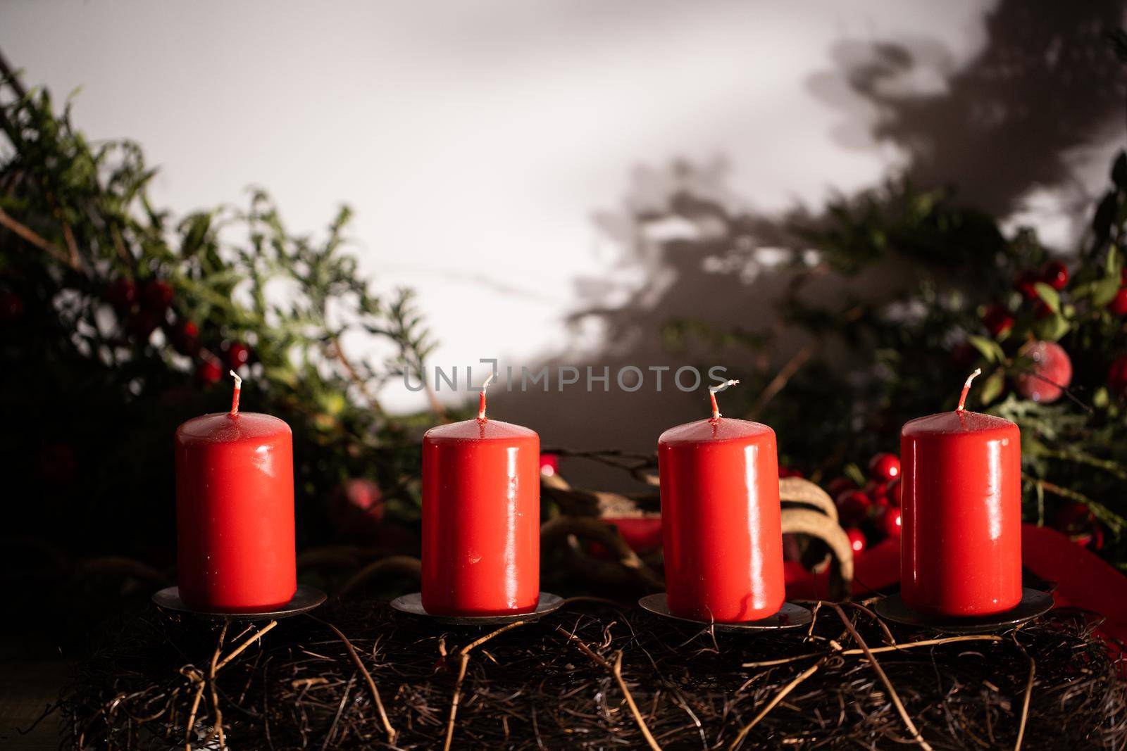 Red candles in the glow of bright light decorate a small space in the living room during Christmas.