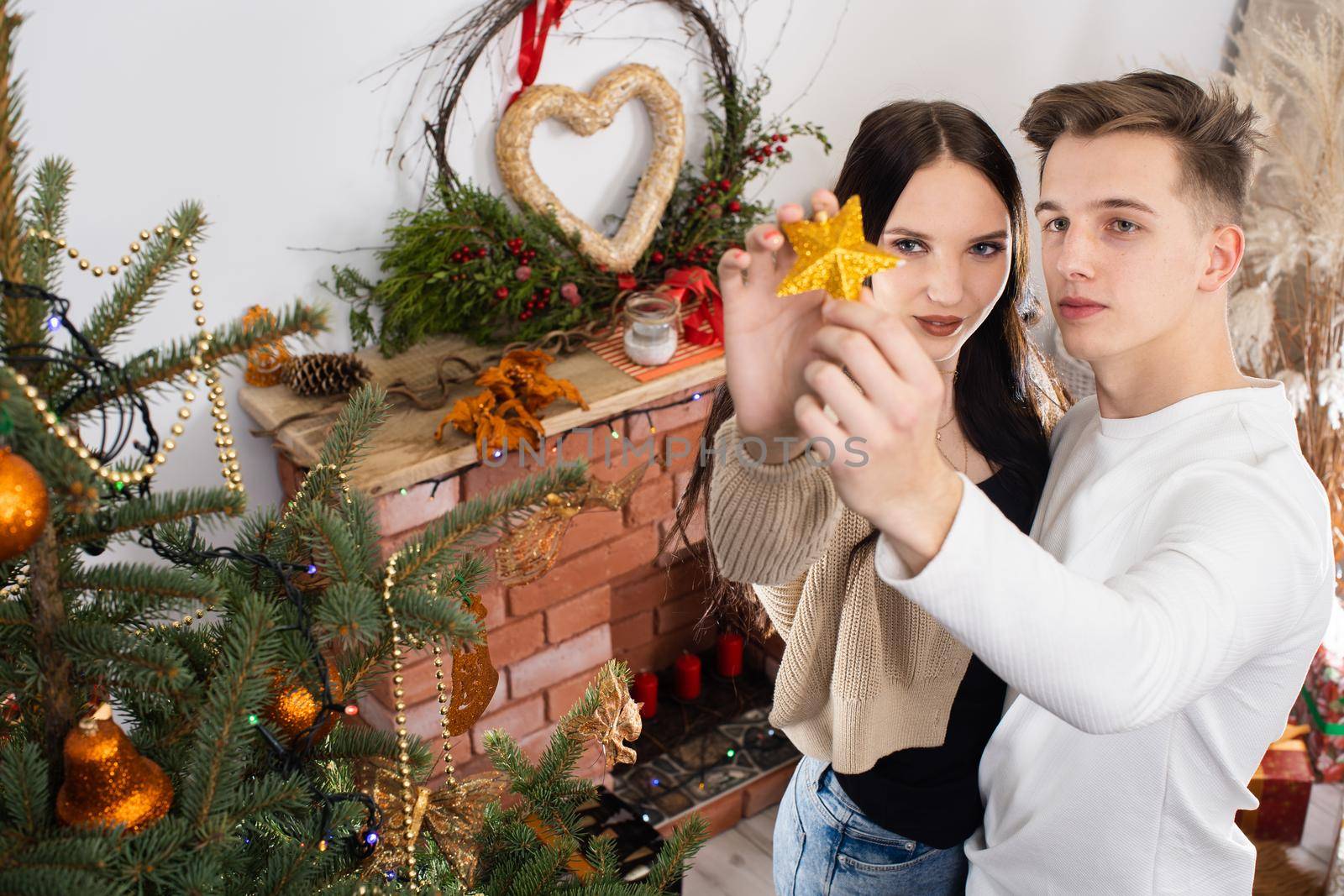 The bride and groom will continue to decorate the Christmas tree. Decoration of a Christmas tree for Christmas in December.