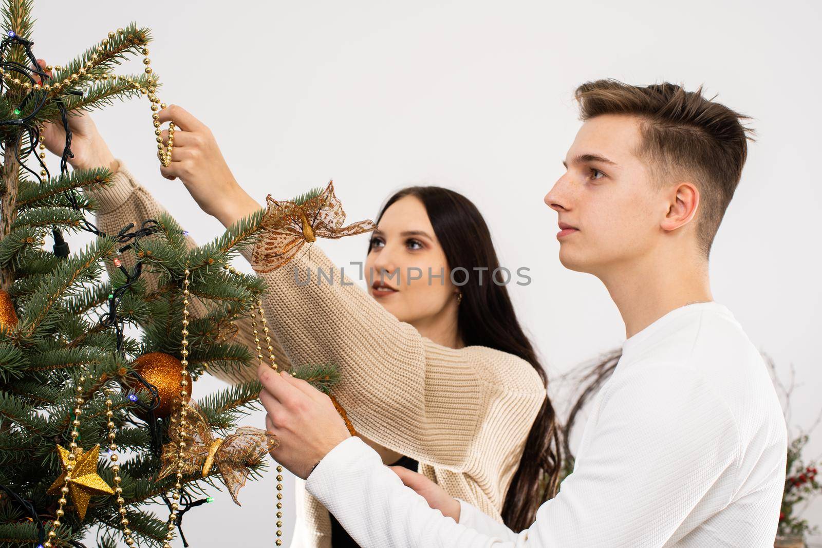 Couple in love while decorating the Christmas tree for Christmas. Smiling young people.