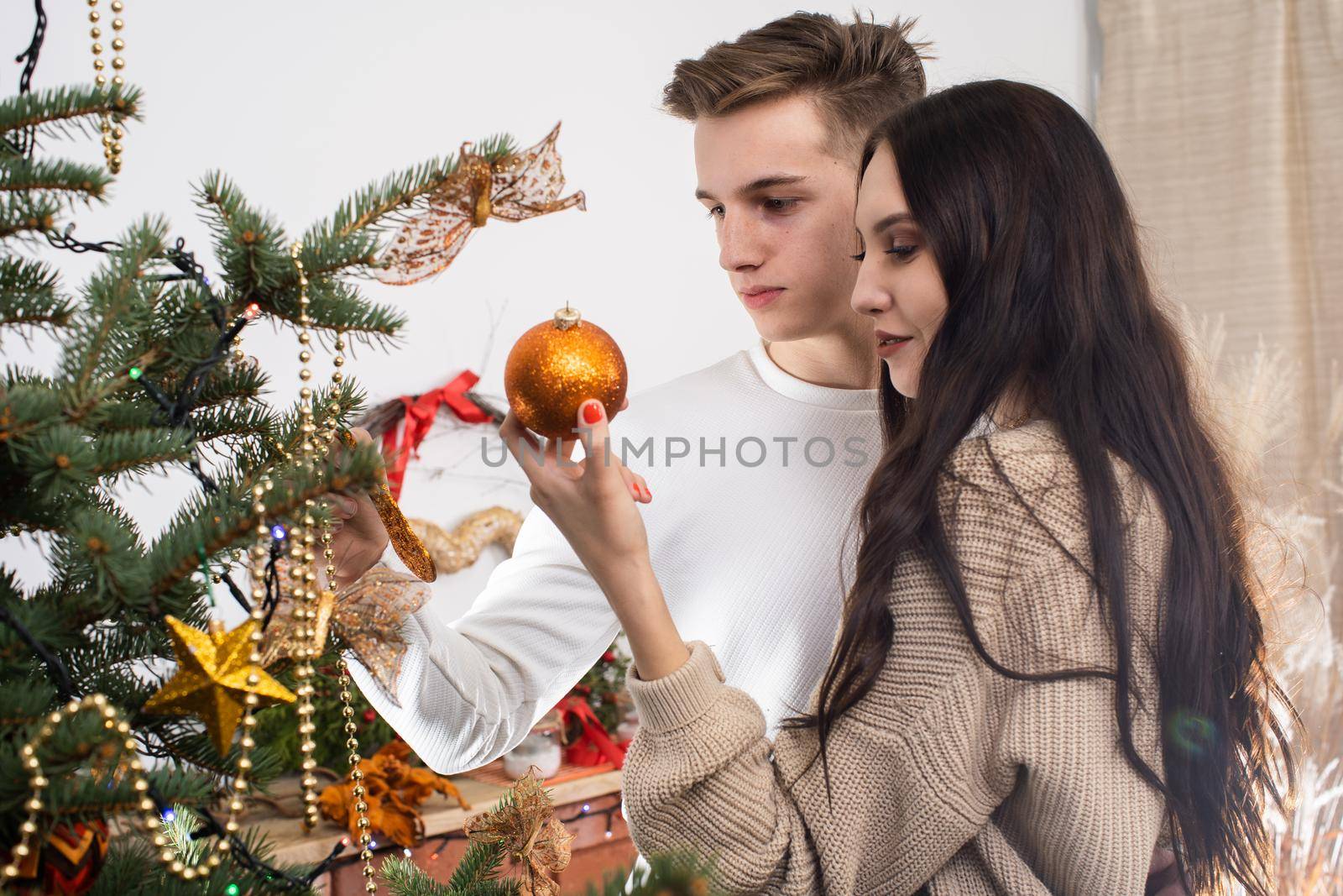 Couple in love while decorating the Christmas tree for Christmas. Smiling young people.