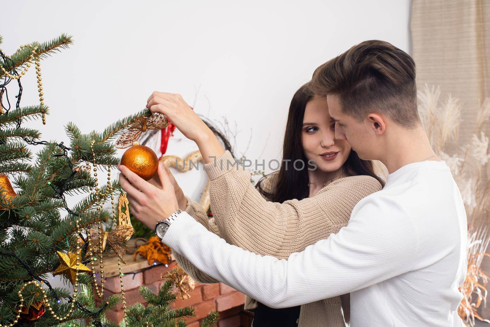 Couple in love while decorating the Christmas tree for Christmas. Smiling young people.