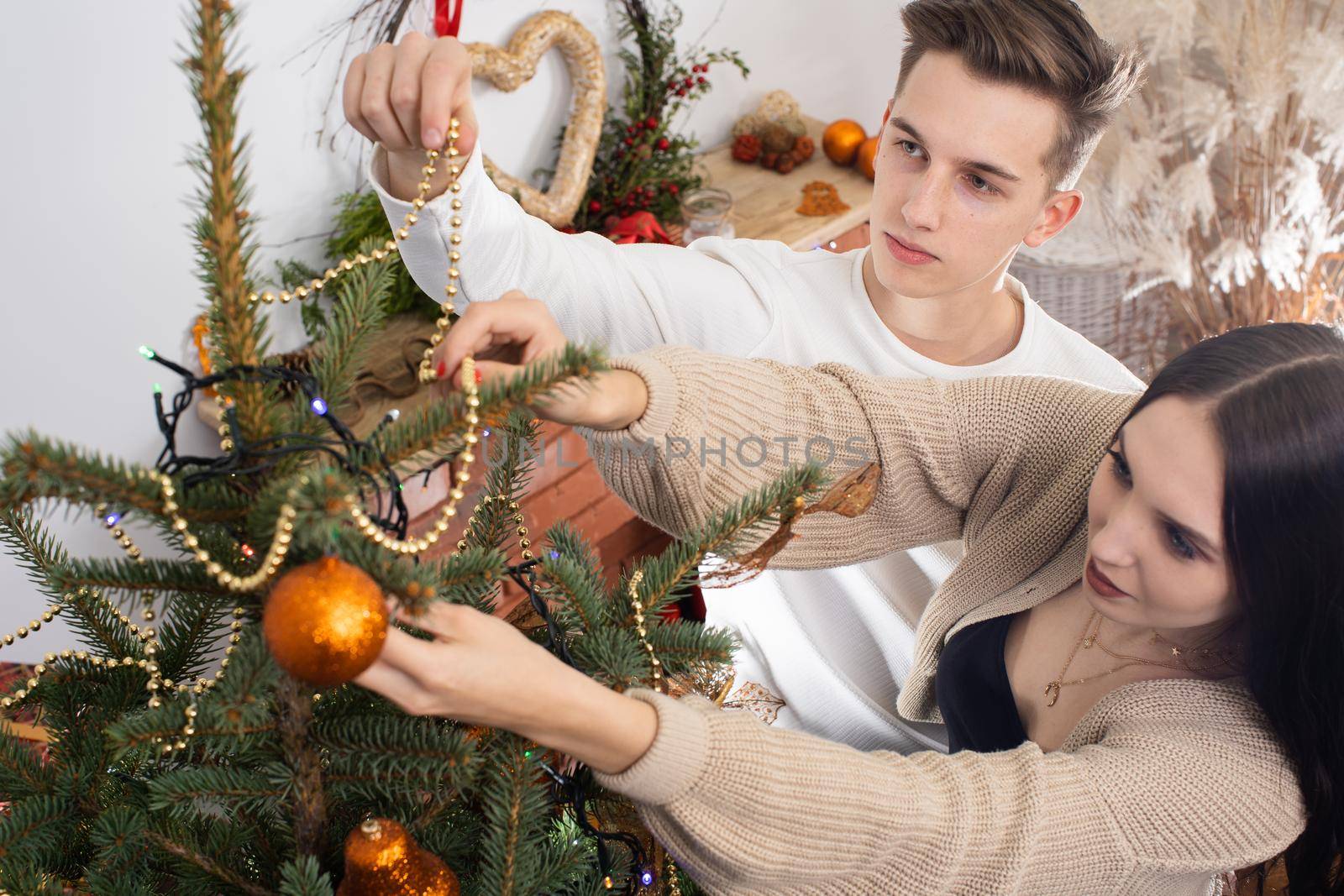 Couple in love while decorating the Christmas tree for Christmas. Smiling young people.