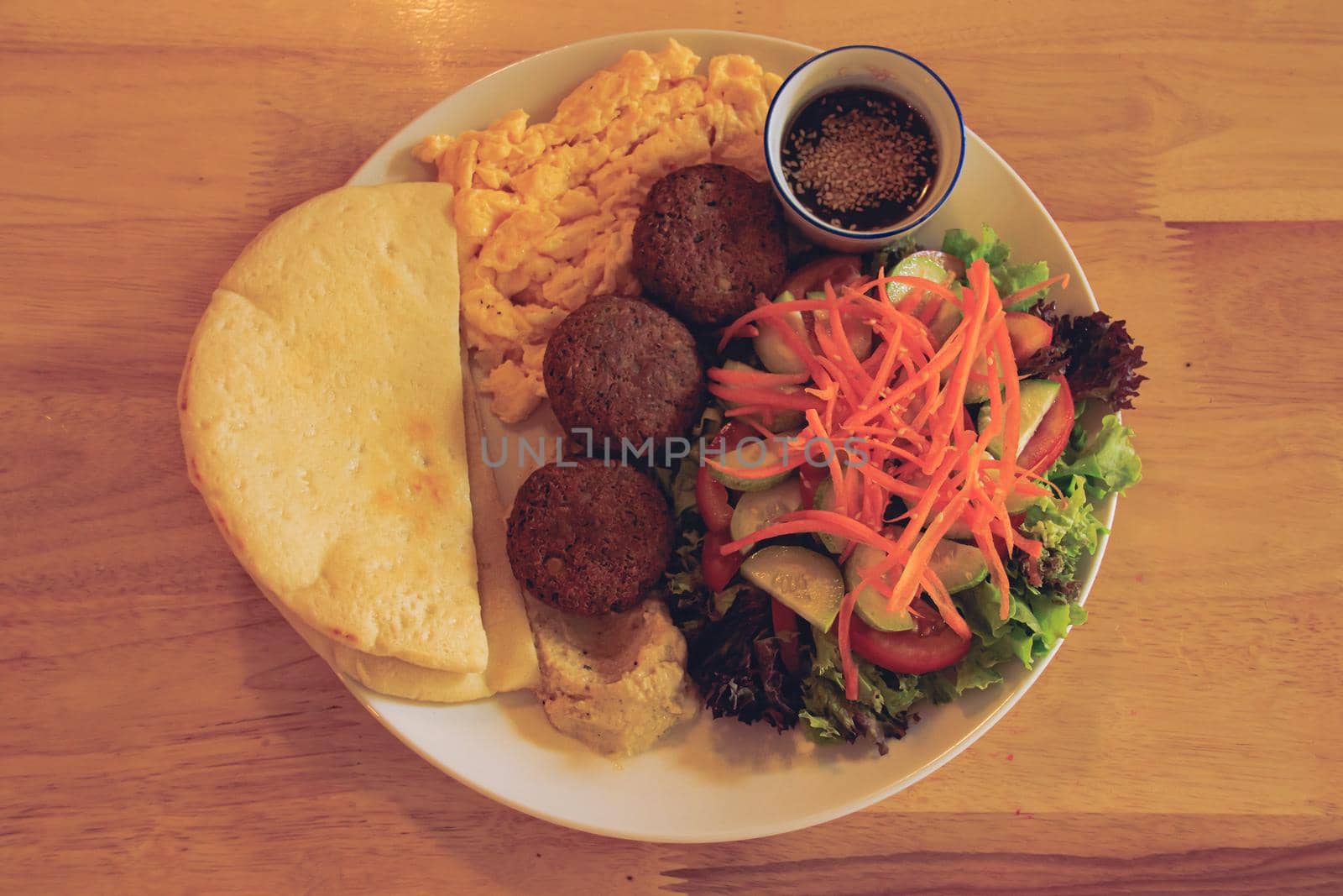 A plate full of falafel balls, pita bread, scrambled eggs and raw vegetable salad for a healthy high protein ovo-vegetarian ketogenic breakfast