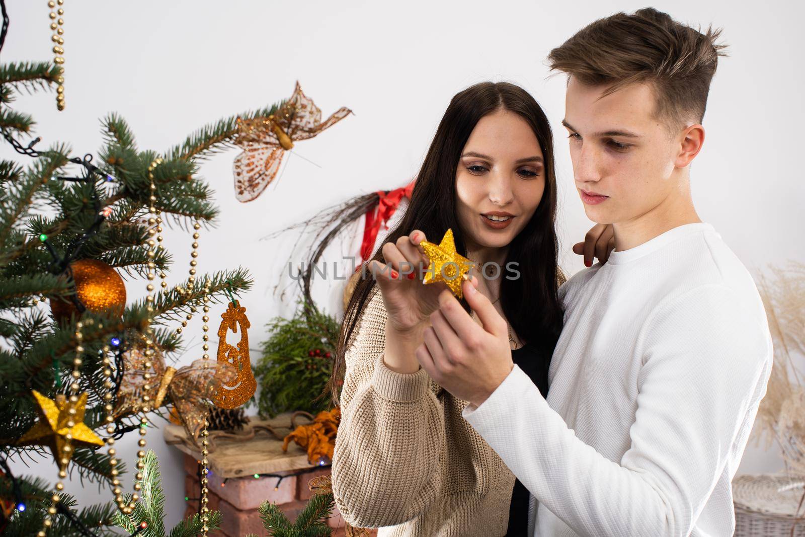 The bride and groom will continue to decorate the Christmas tree. Decoration of a Christmas tree for Christmas in December.