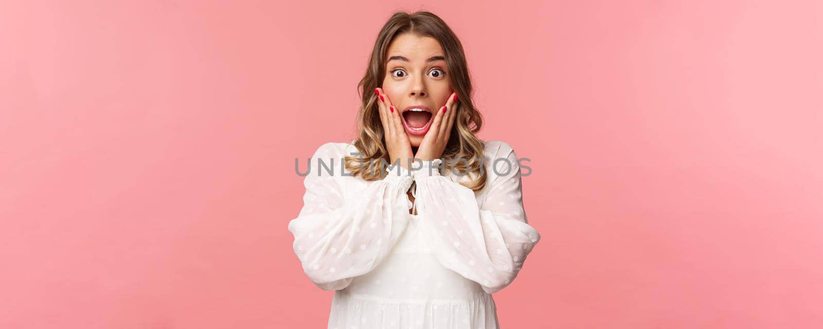 Happy and surprised blond girl hear awesome news, gasping speechless staring camera with hands on cheeks, being impressed and stunned over great event, standing pink background by Benzoix