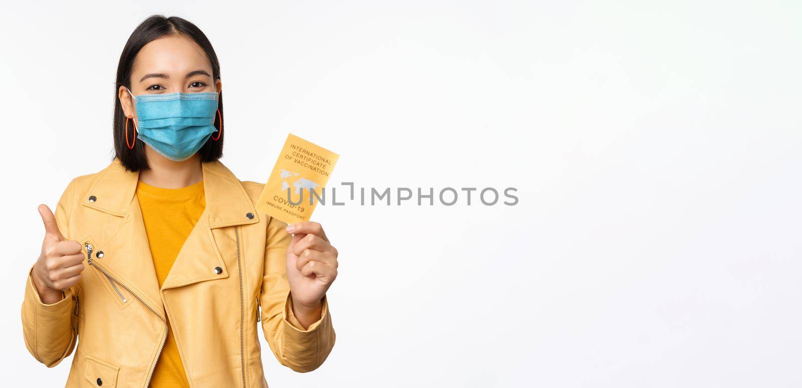 Hey you got point. Cheerful cute asian lively girl dark short haircut pointing camera finger-pistol smiling broadly, encourage friend make move, congratulate coworker good job, stand blue background.