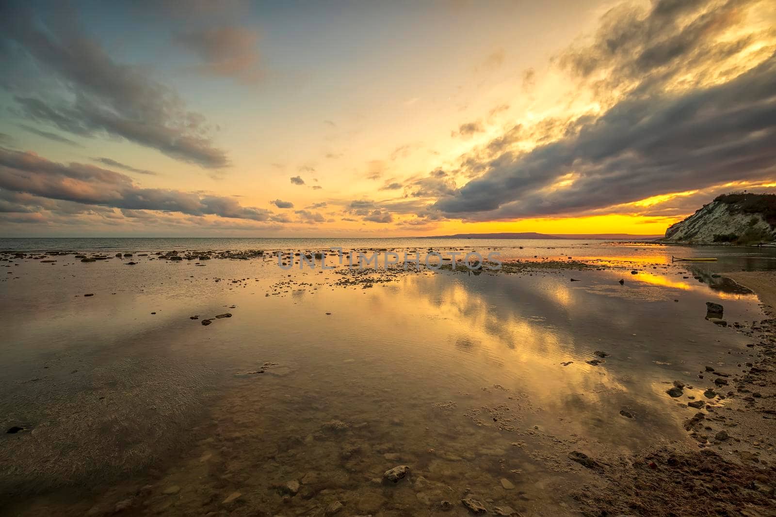 Stone beach at sunset. Twilight sea and sky. Dramatic sky and clouds. Nature landscape.