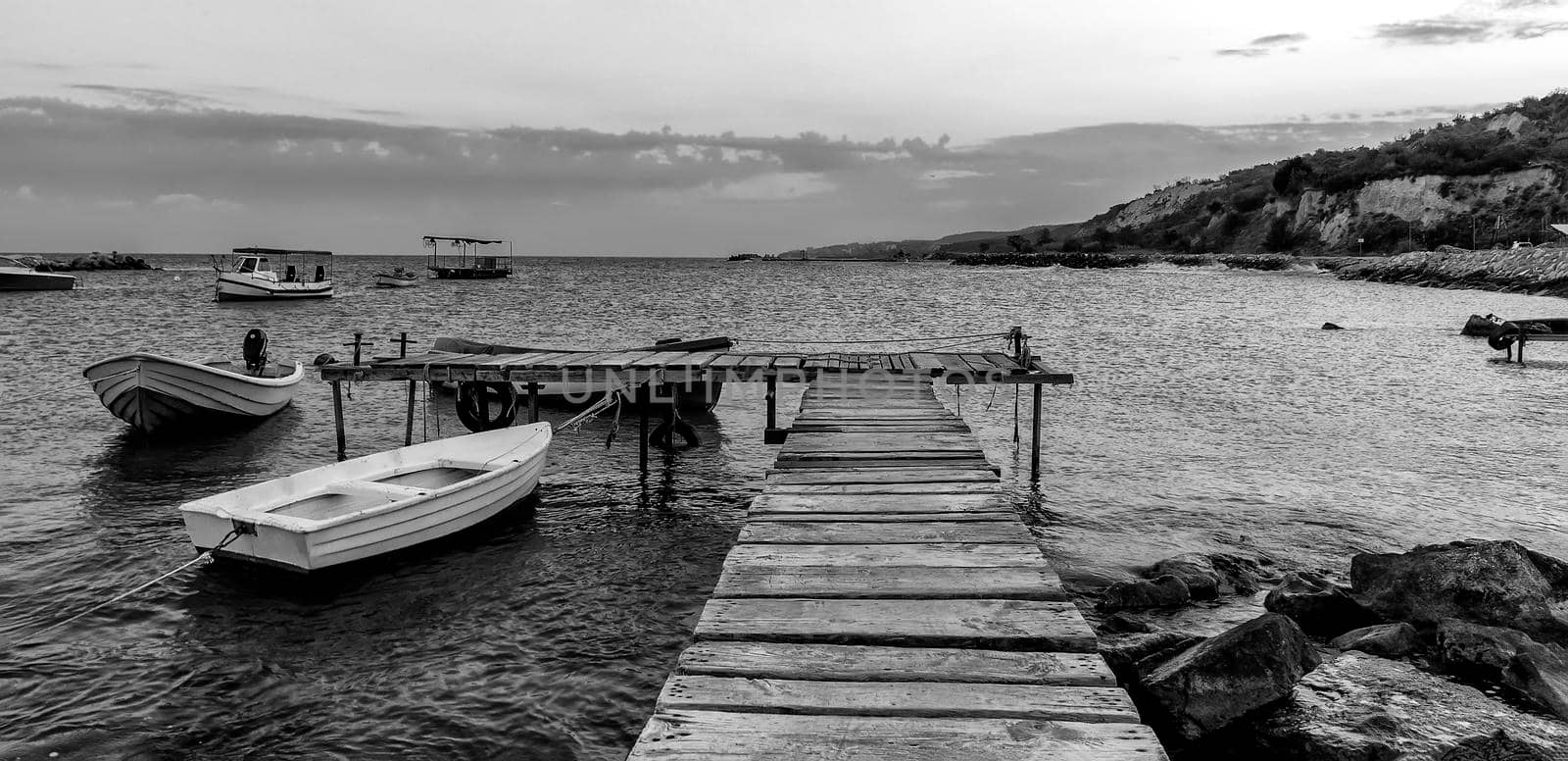 Black and white panoramic view of wooden pier and  boats 