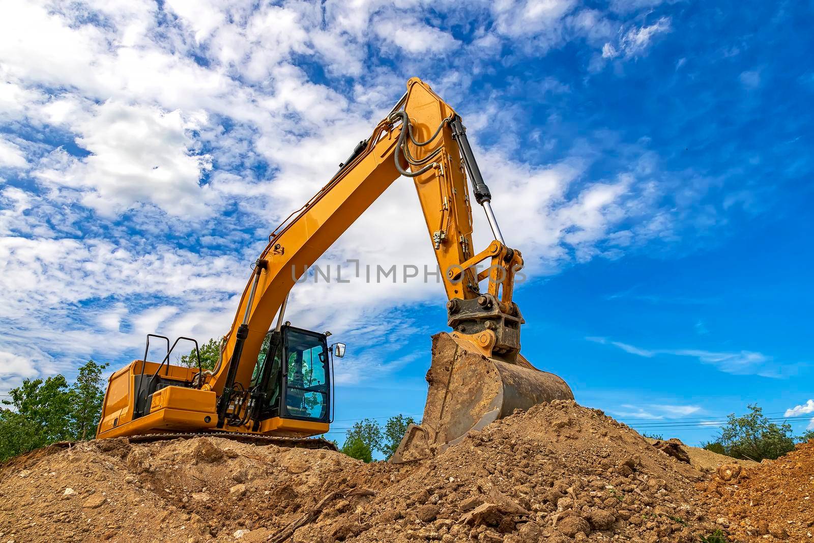 A stopping yellow excavator for rest, at fluffy clouds