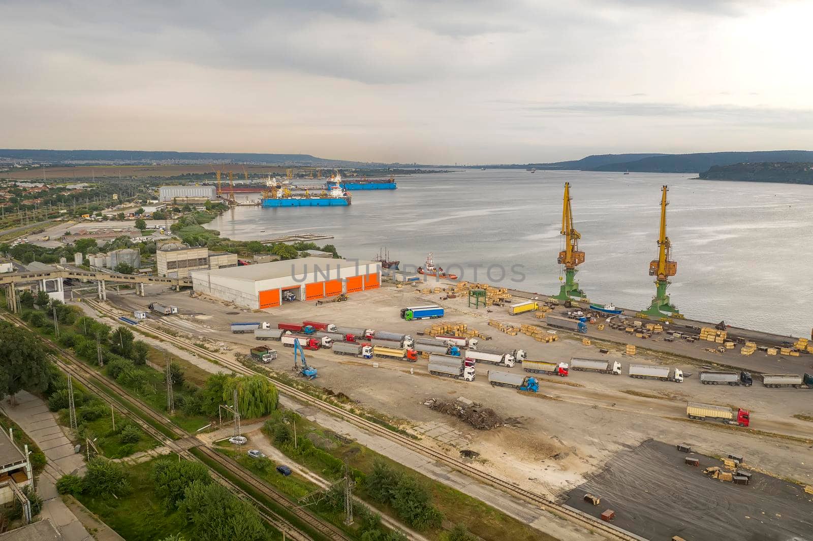 Trucks and port cranes ready to load from cargo ships. Horizontal view