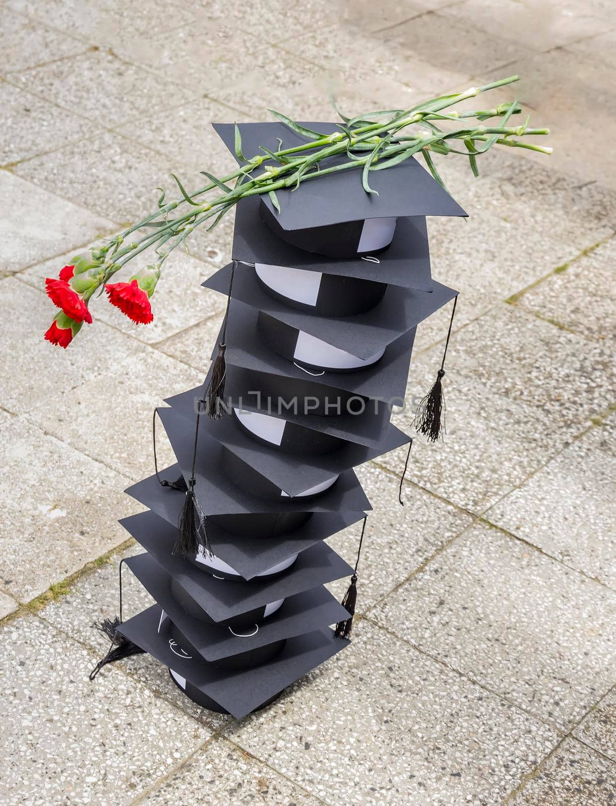 Many graduation hats on top of each other and flowers. Graduating concept. by EdVal