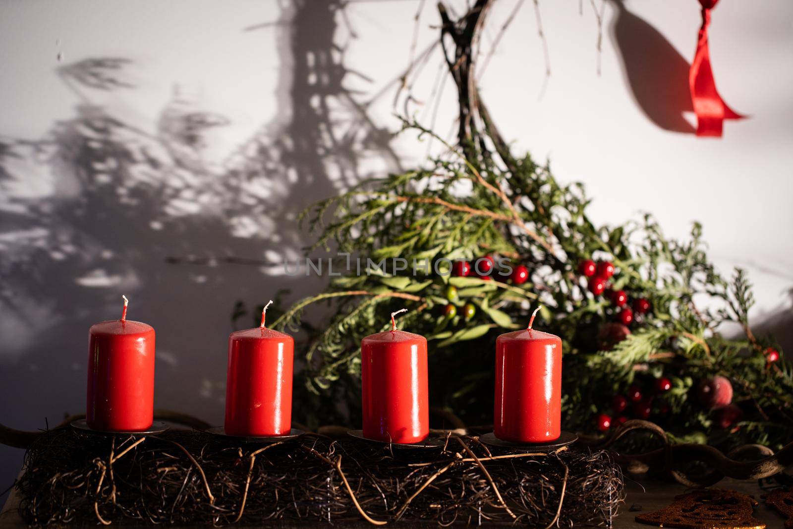 Red candles in the glow of bright light decorate a small space in the living room during Christmas.