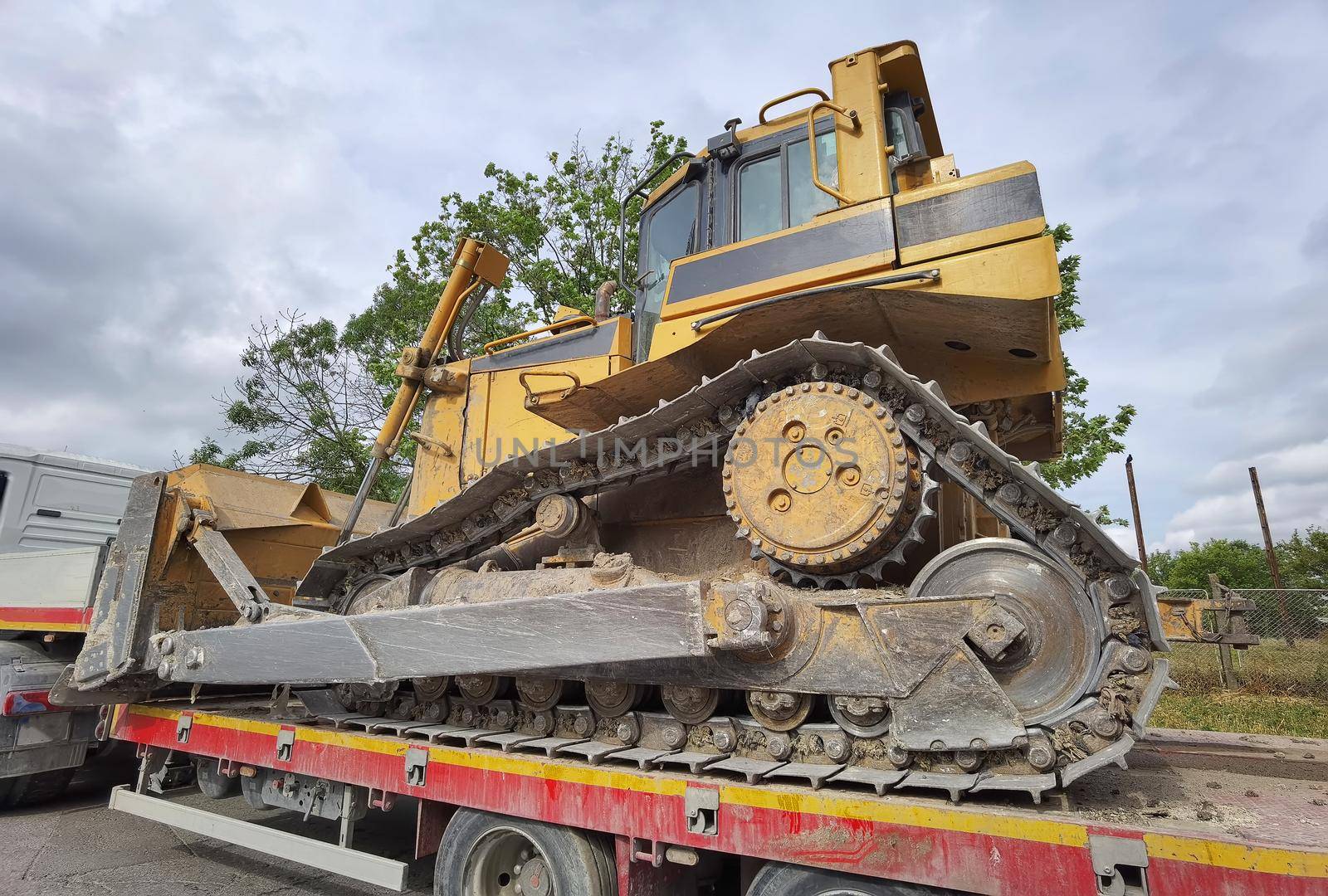 Trailer truck with long platform transport the Excavator. Earth mover backhoe on heavy duty flatbed vehicle for transported.