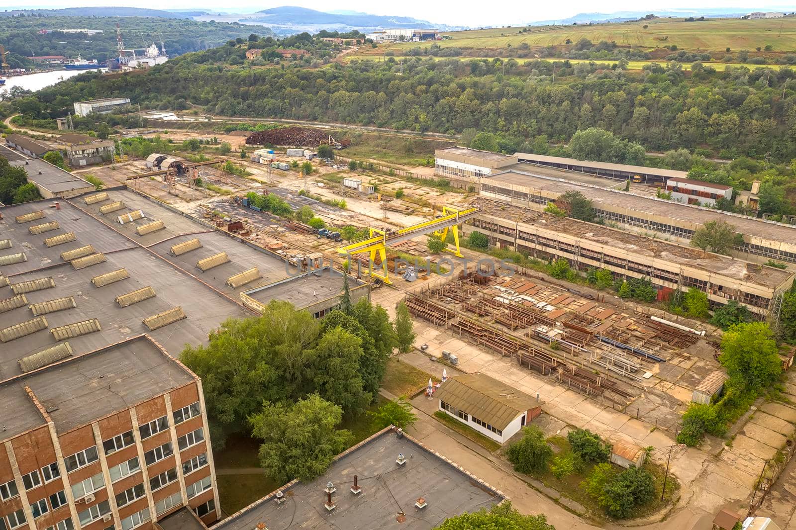aerial view from drone of factory with warehouse of steel elements and crane