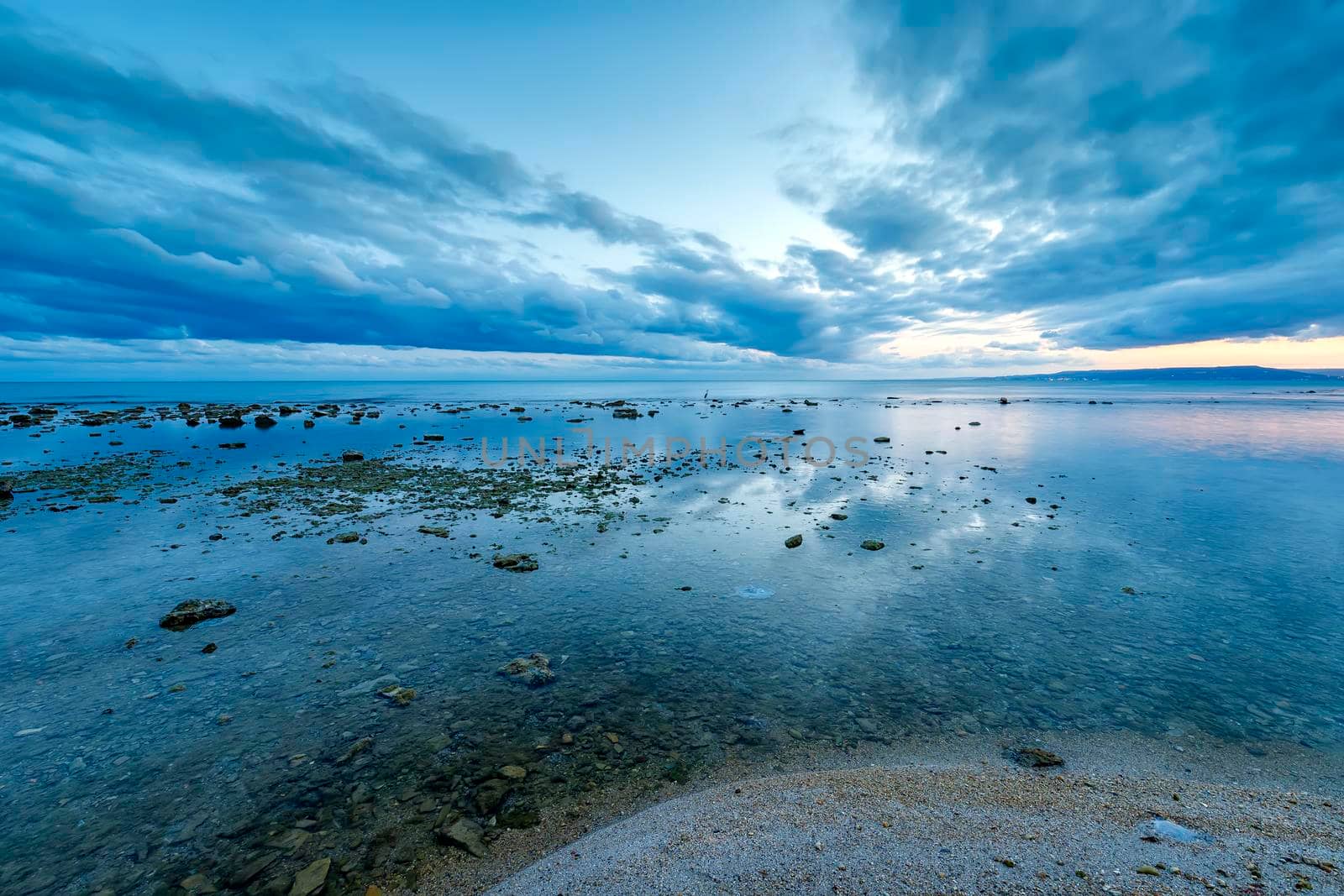 stunning landscape at calm sea water with water reflection. Blue hour