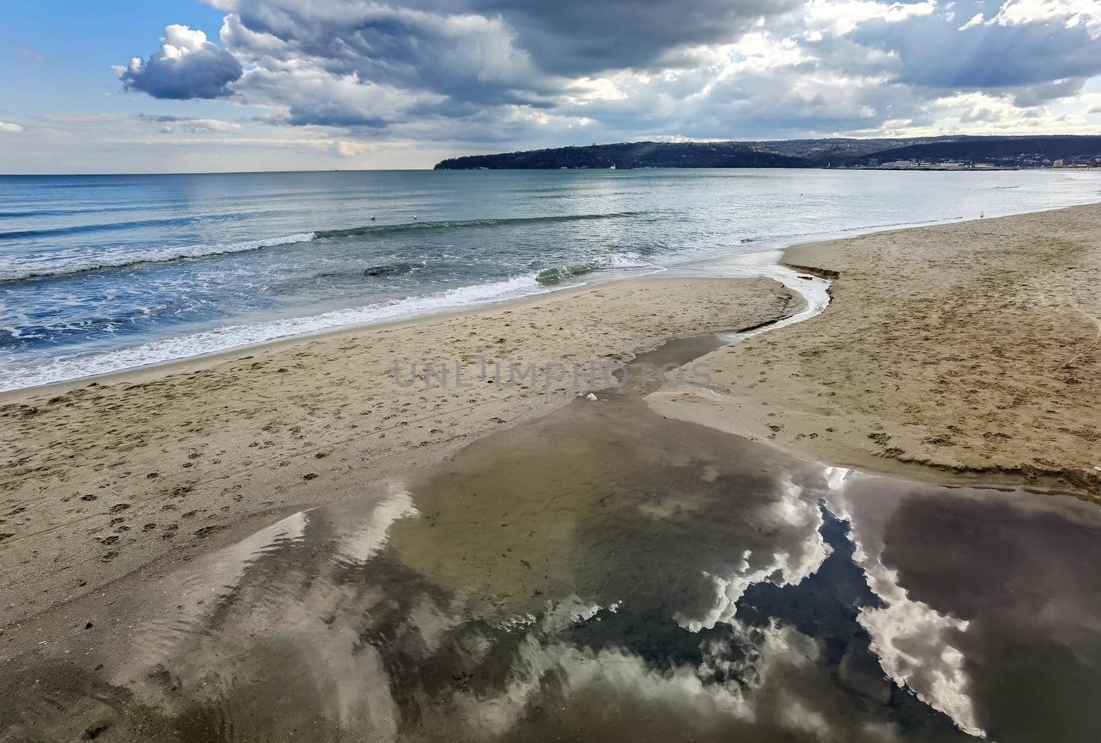 A small brook through sea sand with sky reflection