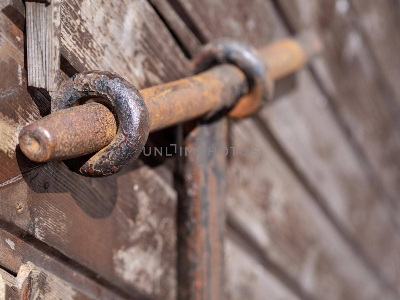 Old rusty metal deadbolt on a wooden door. close-up