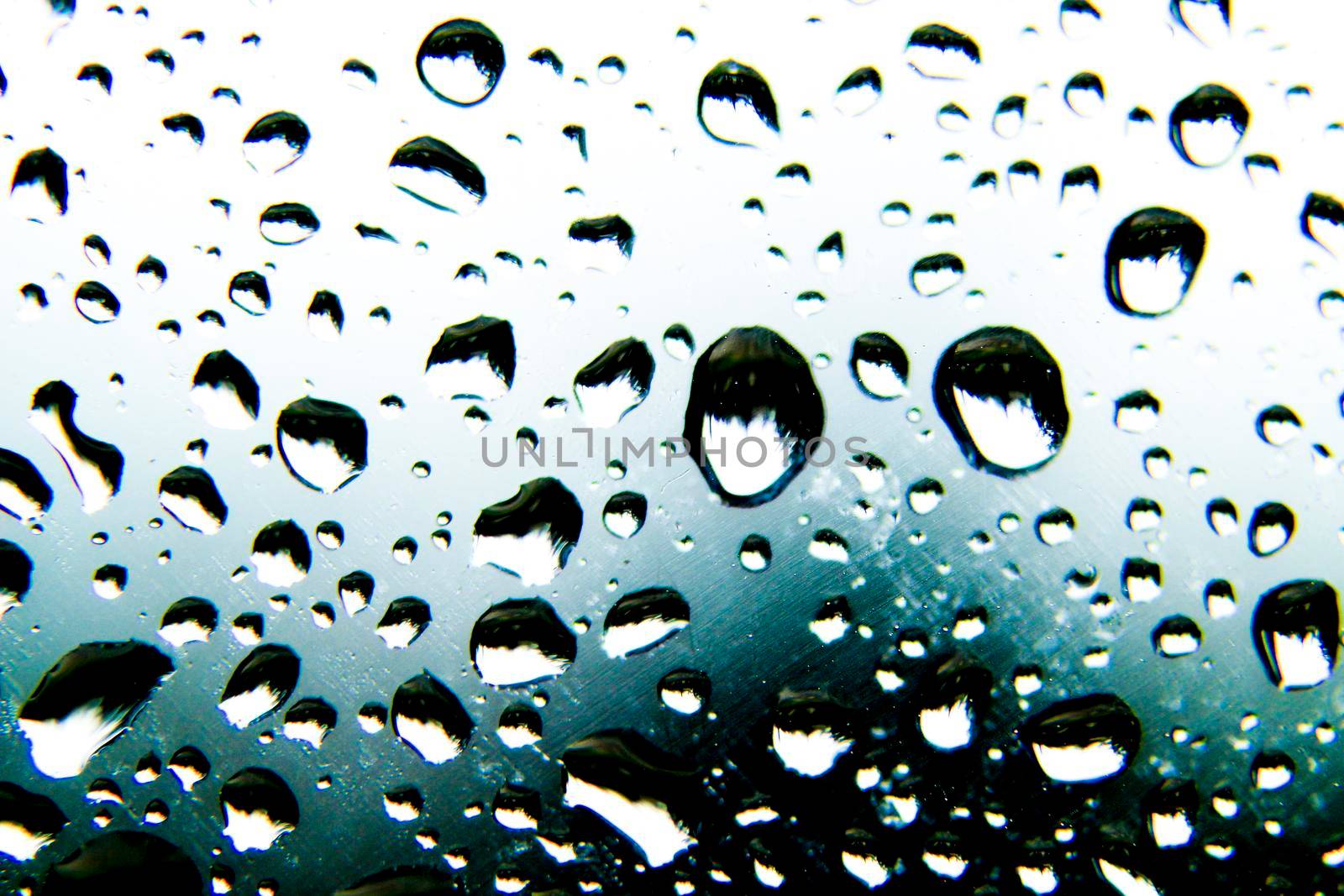 Raindrops on window pane on a cold and cloudy day of winter