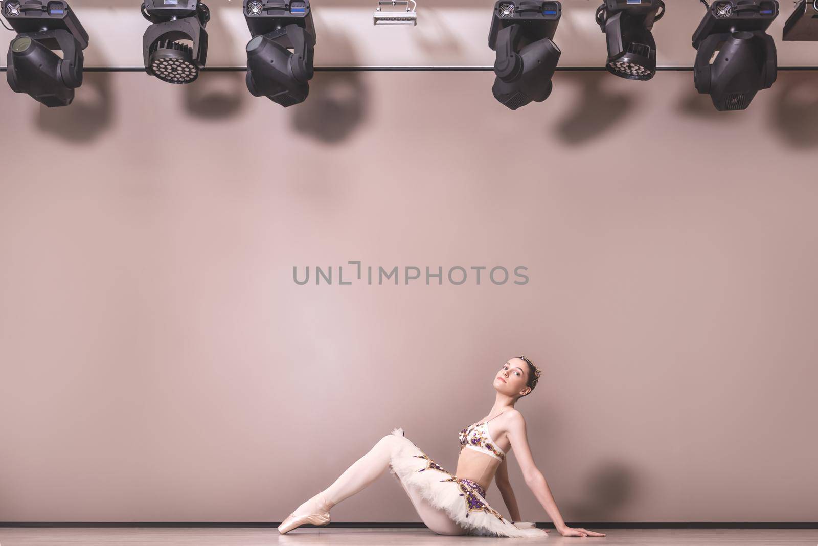 young beautiful graceful caucasian ballerina practice ballet positions in tutu skirt. Classical Ballet dancer sitting on the floor in the studio