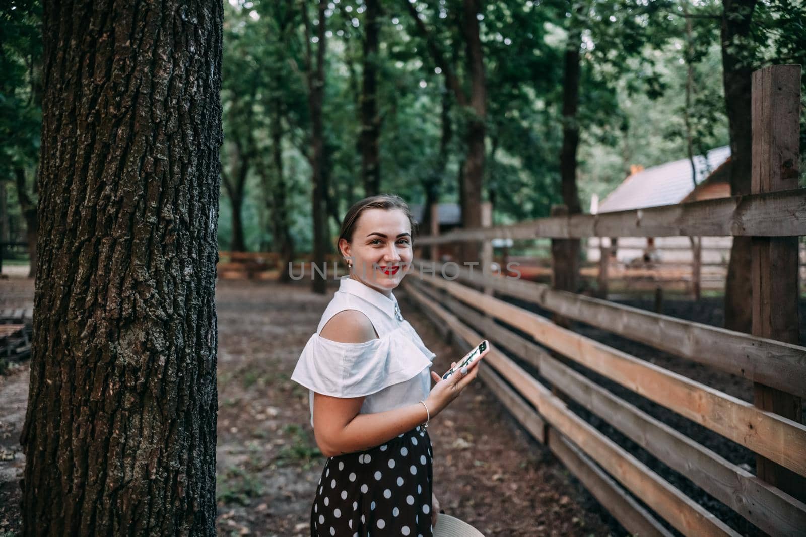 photo of a smiling blonde in the forest with a phone, who is going to take a photo, a beautiful summer forest