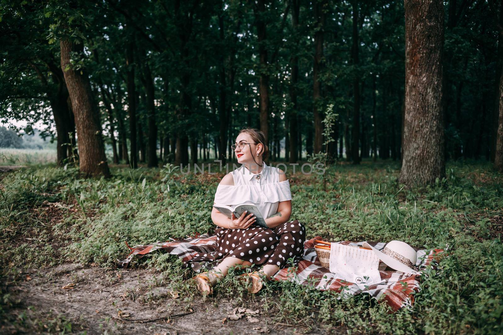 a girl with glasses reads a book in a summer forest. by mosfet_ua