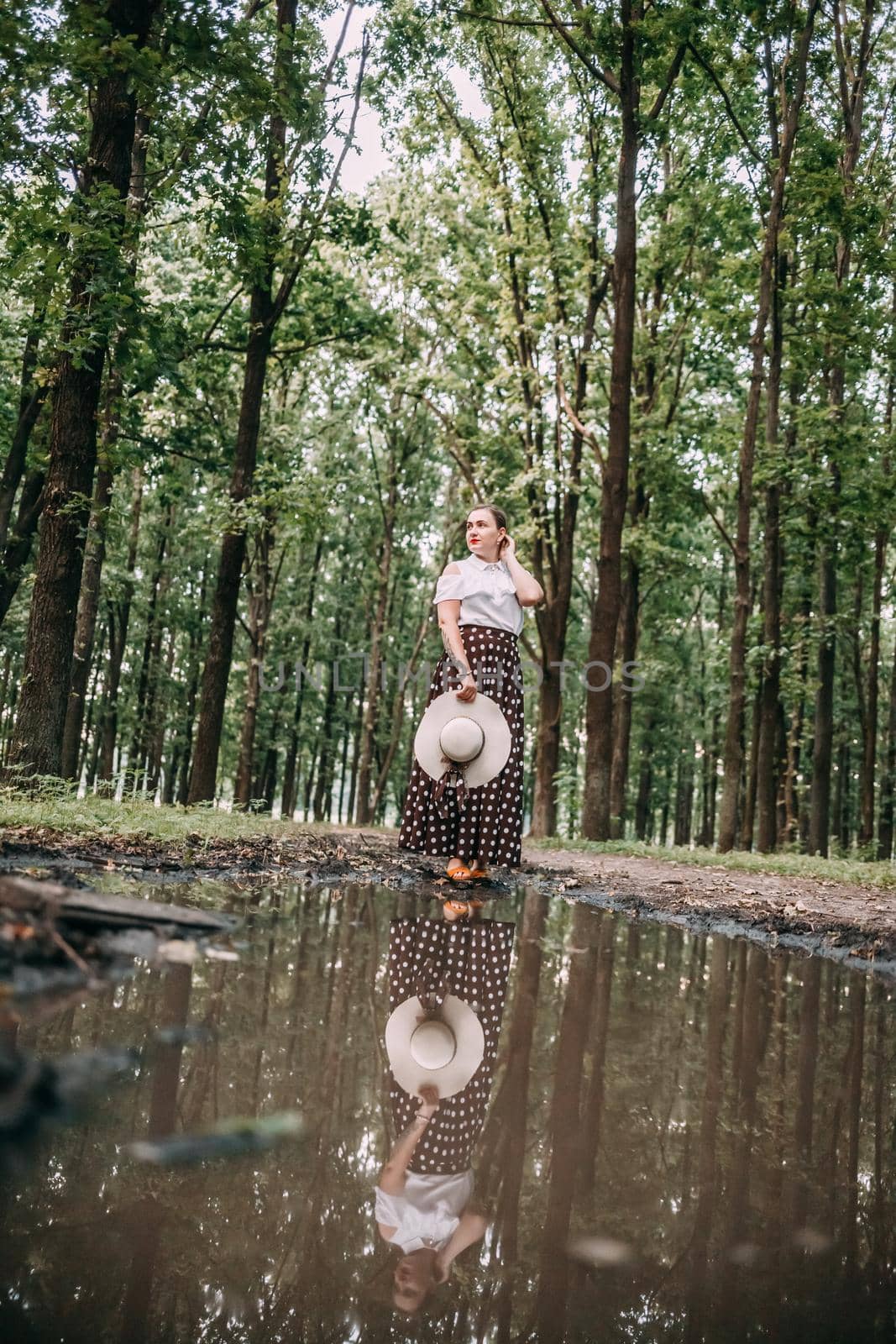 photo of a girl in the reflection of a puddle, in the forest.