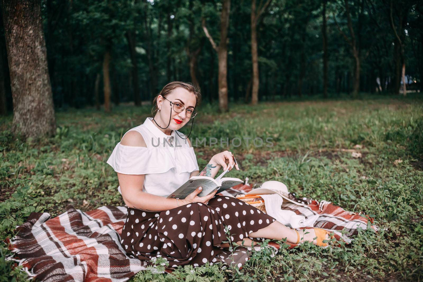 a girl with glasses reads a book in a summer forest. by mosfet_ua