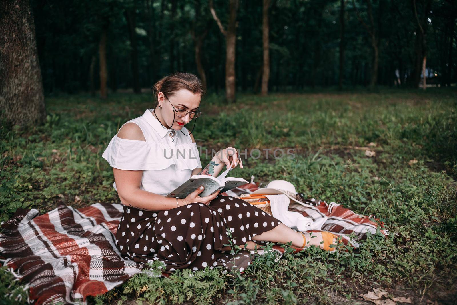 a girl with glasses reads a book in a summer forest