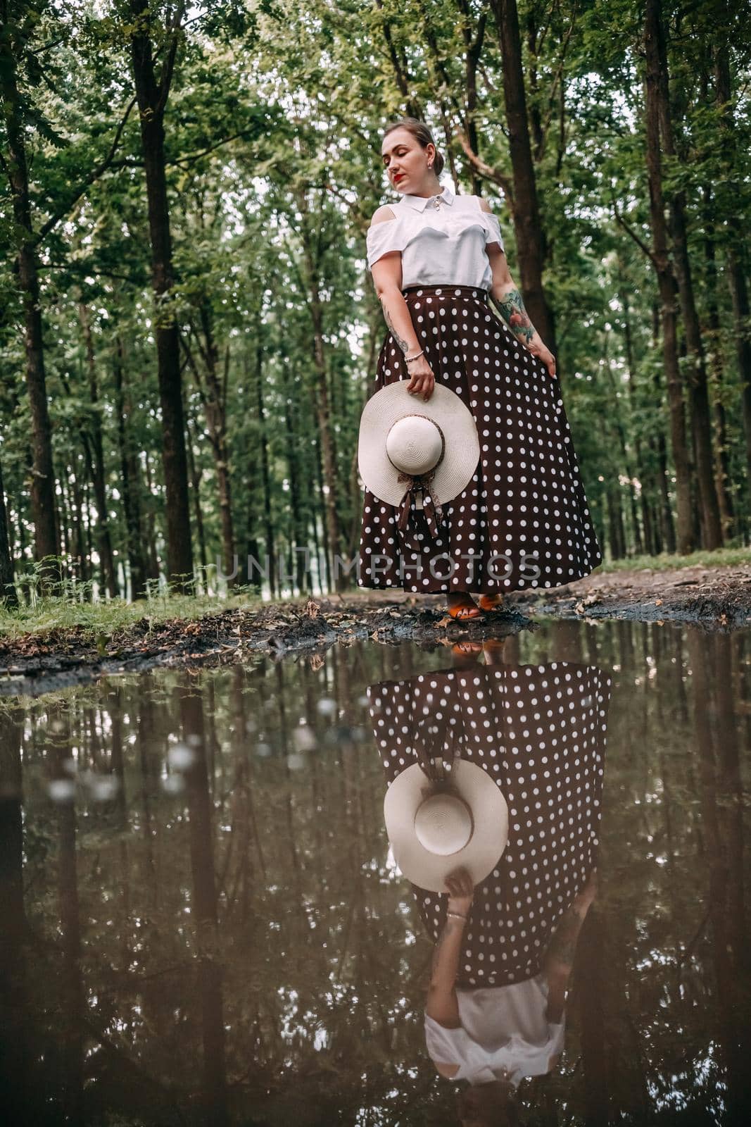 photo of a girl in the reflection of a puddle, in the forest.