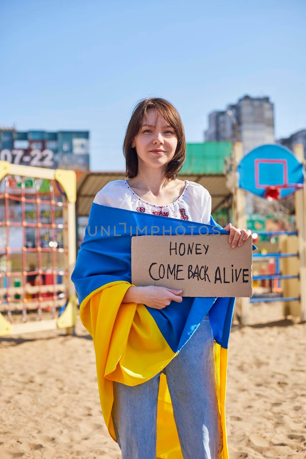 Portrait of a joyful Ukrainian woman holding a child and a Ukrainian flag. The girl is waiting for her husband from the war. War between Russia and Ukraine