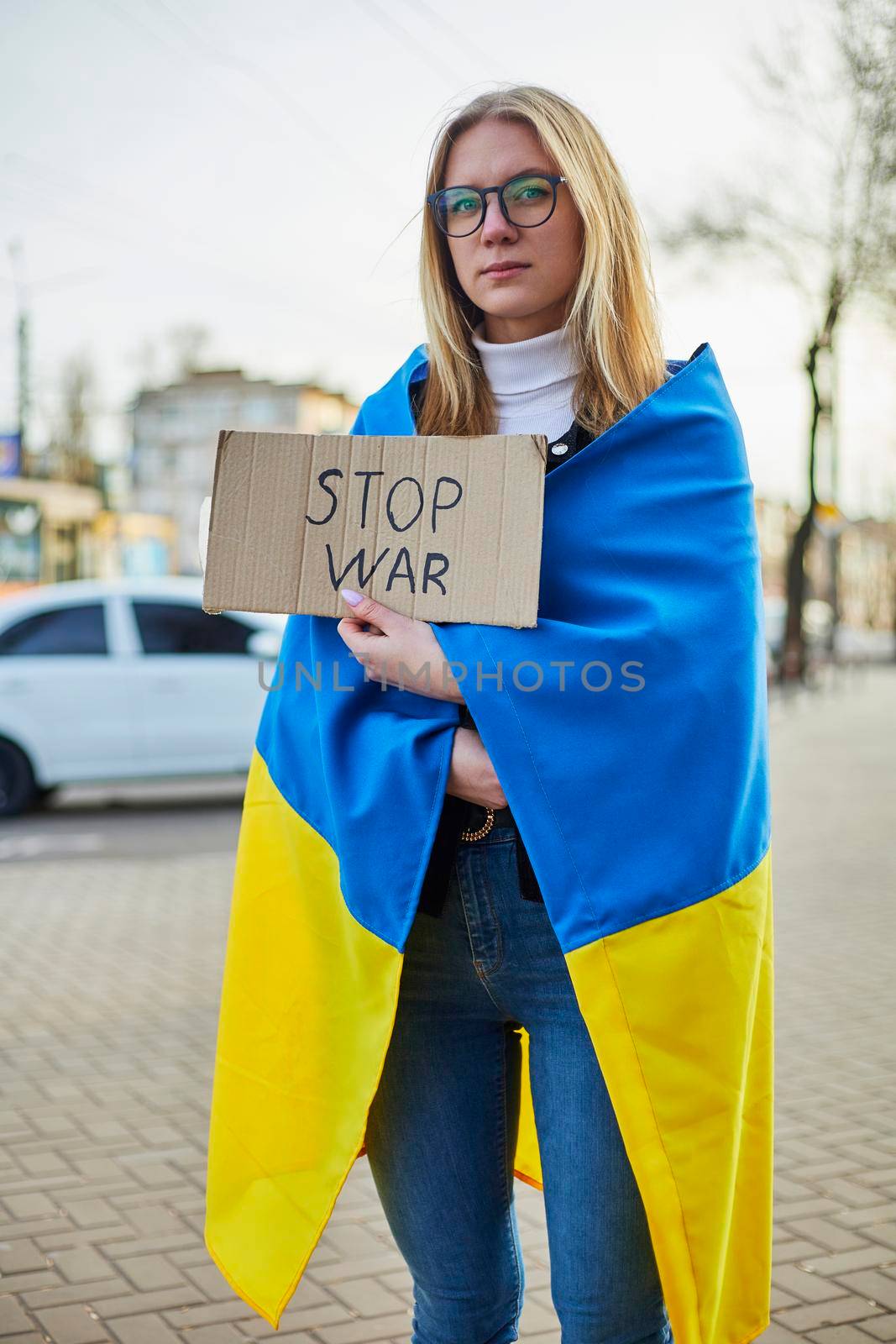 Portrait of a joyful Ukrainian woman holding a Ukrainian flag and a sign. The girl is waiting for her husband from the war. War between Russia and Ukraine. by mosfet_ua