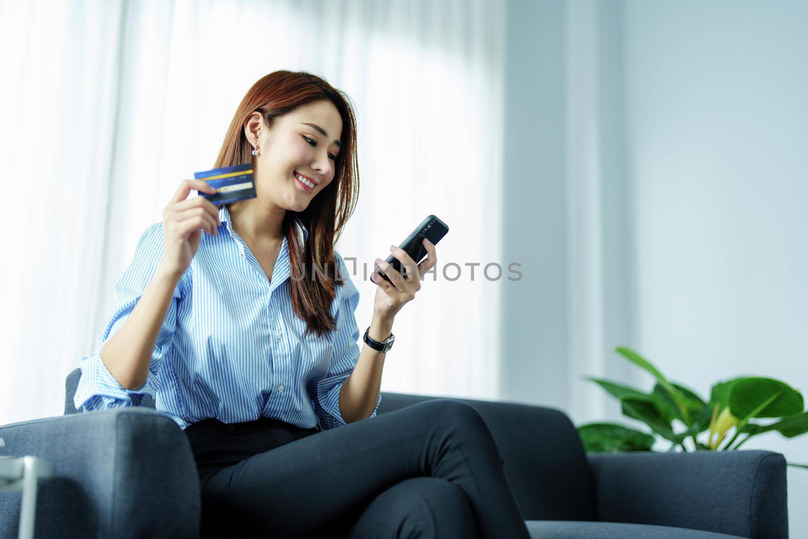 Online Shopping and Internet Payments, Portrait of Asian woman are using their mobile phones and credit cards to shop online or conduct errands in the digital world. by Manastrong