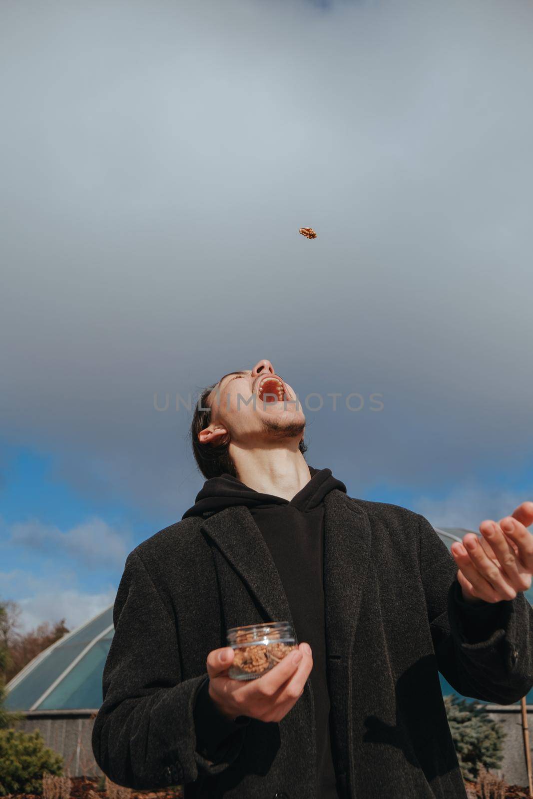 Young gay hipster eating peanuts at the street smiling happy sunglasses by Symonenko