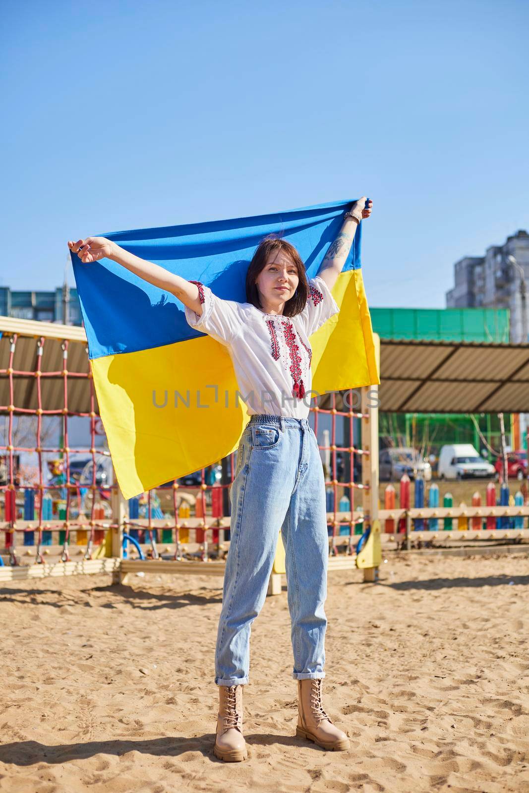 Portrait of a joyful Ukrainian woman holding a child and a Ukrainian flag. The girl is waiting for her husband from the war. War between Russia and Ukraine. by mosfet_ua