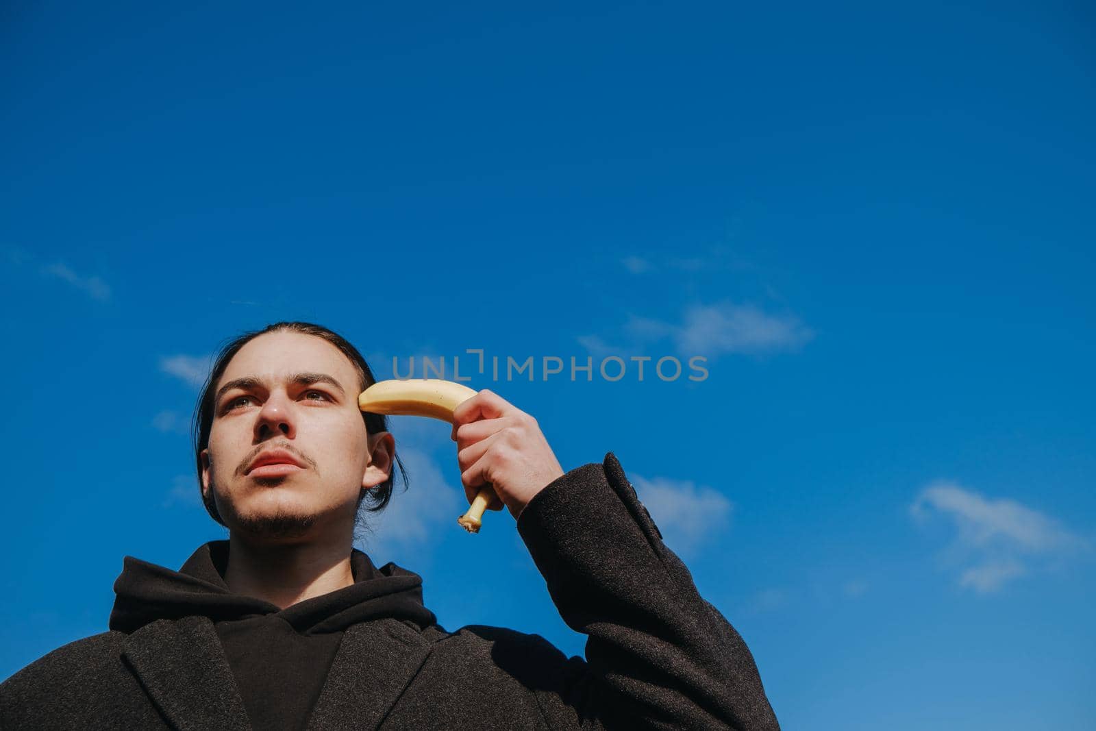 young gay hipster make banana suicide at the street. sky