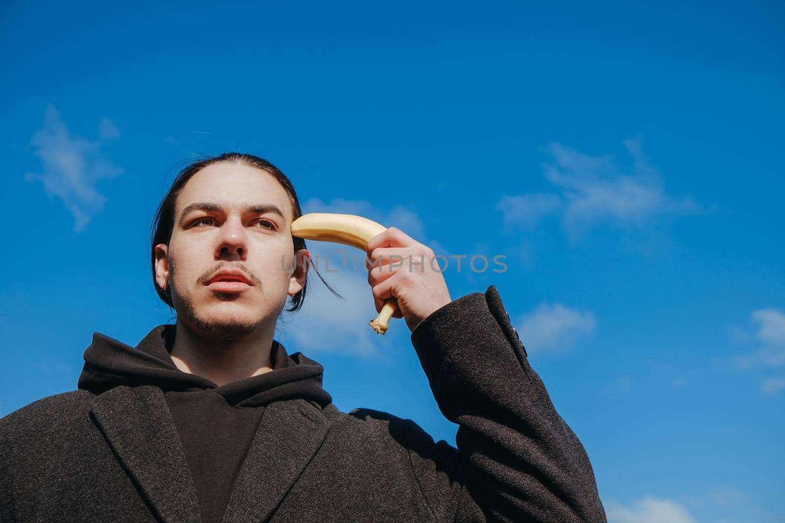 young gay hipster make banana suicide at the street. sky