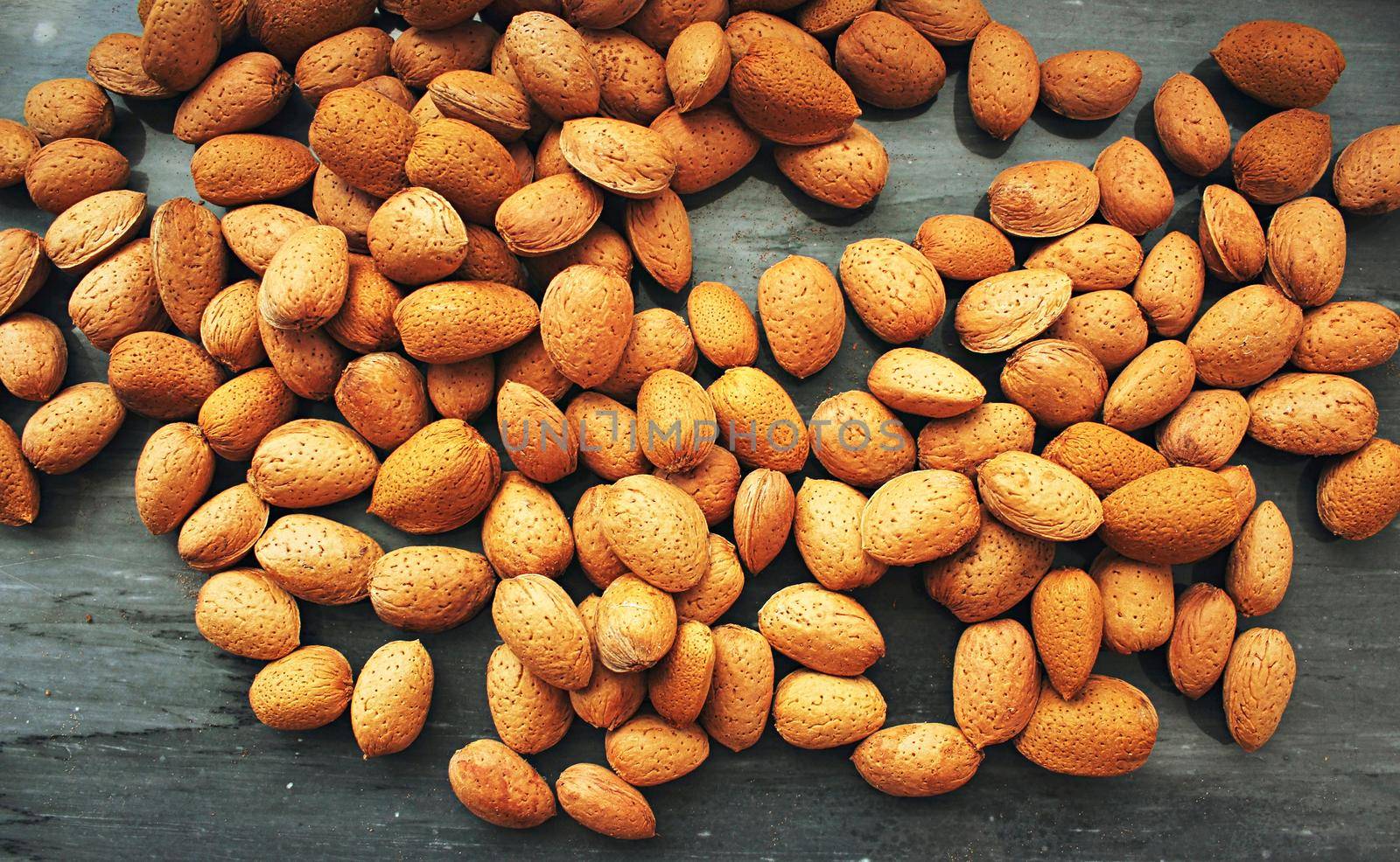 Raw almonds in their husks against a black marble background