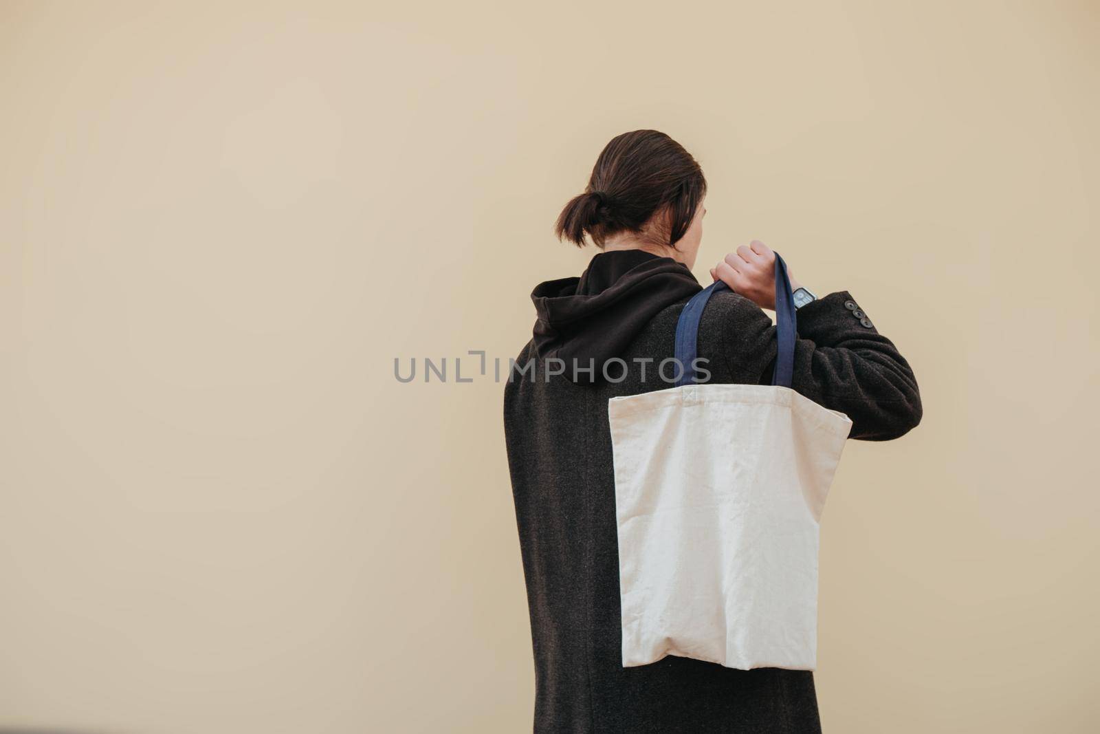 Young man holding textile bag on color background, closeup. Mockup for design hipster