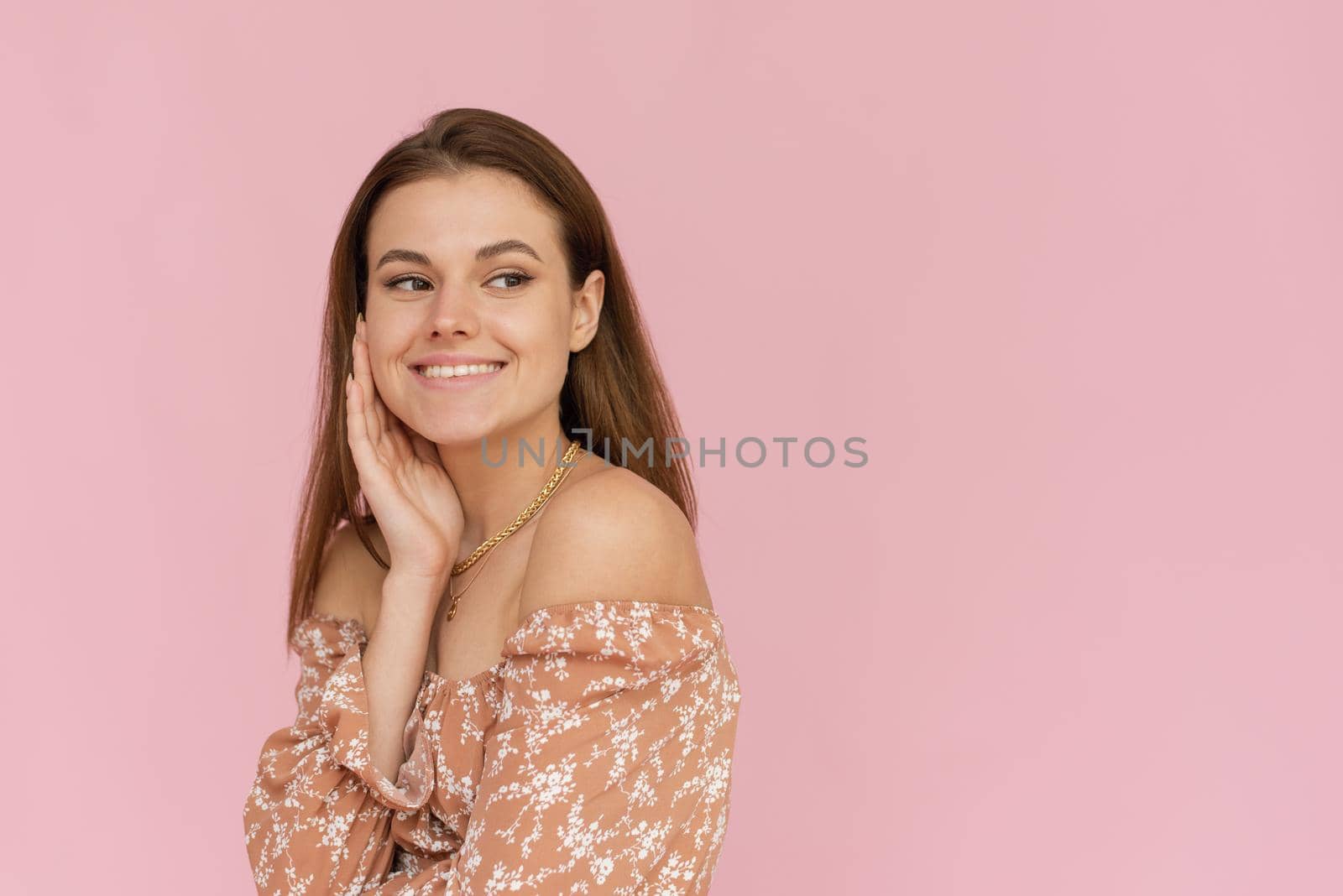 Pretty young woman in a beige dress on a pink background with copy space. Summer concept